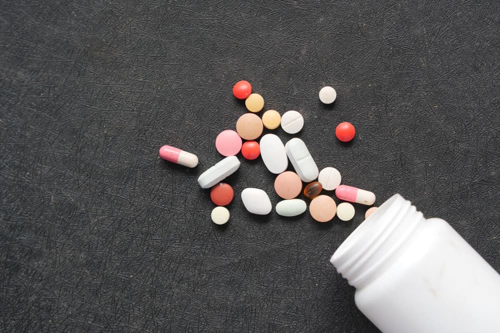 Verschiedene Tabletten und Kapseln neben einer Dose